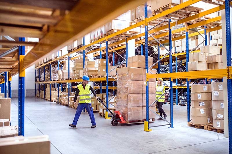 Operatori in un magazzino con scaffalature e transpallet